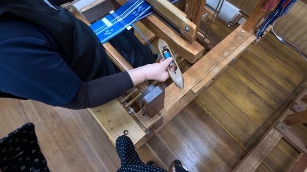 ミンサー織り体験で職人さんからレクチャーを受けている様子